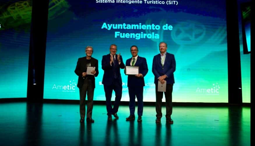 El Ayuntamiento de Fuengirola ha recibido una mención de honor de AMETIC por su proyecto de inteligencia turística durante la celebración de Digital Tourist 2026, uno de los principales encuentros nacionales sobre innovación y tecnología aplicada al turismo. Este congreso reúne anualmente a administraciones públicas, destinos turísticos, empresas tecnológicas y expertos nacionales e internacionales en torno a estas materias. El reconocimiento, recibido en Benidorm por el primer teniente de alcalde, Rodrigo Romero, pone en valor la apuesta de Fuengirola por un nuevo modelo de gestión turística basado en la inteligencia artificial, la integración tecnológica y la mejora de la experiencia del visitante. El galardón distingue el proyecto hasta ahora conocido como `Fuengirola 360´, una iniciativa que integra en un único ecosistema inteligente todas las necesidades que puede tener un turista desde el momento en que planifica su viaje hasta después de regresar a su lugar de origen y compartir su experiencia. Se trata de una nueva manera de entender la relación entre una ciudad y quienes la visitan. Con este proyecto, el Ayuntamiento quiere superar un modelo fragmentado en el que la web turística, la atención en destino y la relación posterior con el visitante funcionaban de manera separada, apostando por conectar las tres etapas del viaje en una única plataforma inteligente, integrada y centrada en las personas. Antes del viaje, el sistema permitirá a los usuarios descubrir Fuengirola mediante canales digitales, contenidos inteligentes y herramientas de planificación dinámica capaces de ofrecer propuestas personalizadas, según sus intereses y necesidades. Durante la estancia, los visitantes contarán con puntos de atención e información disponibles las 24 horas del día en distintos espacios de la ciudad, apoyados por inteligencia artificial y preparados para ofrecer una experiencia accesible, inmediata y útil en varios idiomas. Después del viaje, la plataforma permitirá mantener el vínculo con quienes visitan el municipio gracias a herramientas avanzadas de CRM y fidelización, favoreciendo una comunicación continua entre el destino y el visitante. Todo ello estará integrado en una plataforma tecnológica completa y escalable, orientada a la excelencia en el servicio y basada en la gestión inteligente del destino, el análisis de datos y la inteligencia artificial aplicada al turismo. Además, el proyecto también estará abierto a la participación de los negocios locales que deseen integrarse en esta nueva herramienta, favoreciendo así una mayor conexión entre el tejido empresarial de la ciudad y la experiencia turística de quienes visitan Fuengirola. Con esta distinción, Fuengirola refuerza su posicionamiento como uno de los destinos turísticos más innovadores del país y consolida su apuesta por un modelo turístico más moderno, conectado y adaptado a las nuevas necesidades de los viajeros.